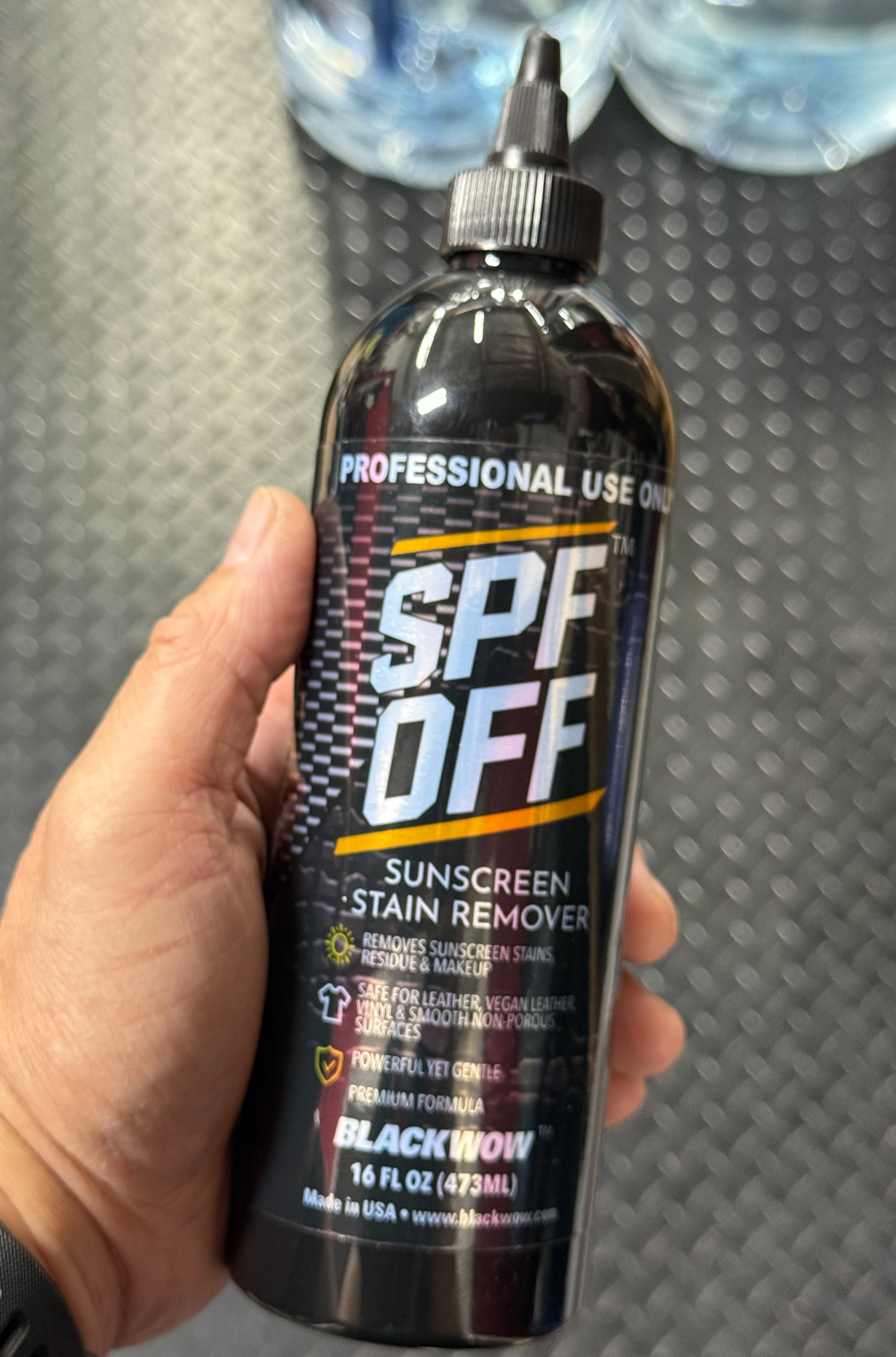 Hand holding SPF OFF 16 oz on diamond plate